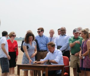 Photo of governor Lamont signing the bill surrounded by people